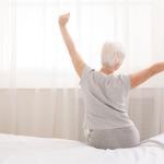 Senior,Woman,Sitting,On,Her,Bed,In,Morning,,Stretching,With